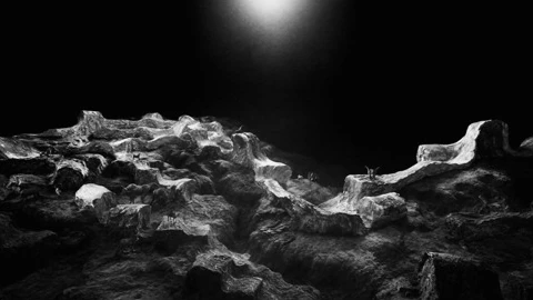 A small pool of light falls over a dark, rocky landscape.