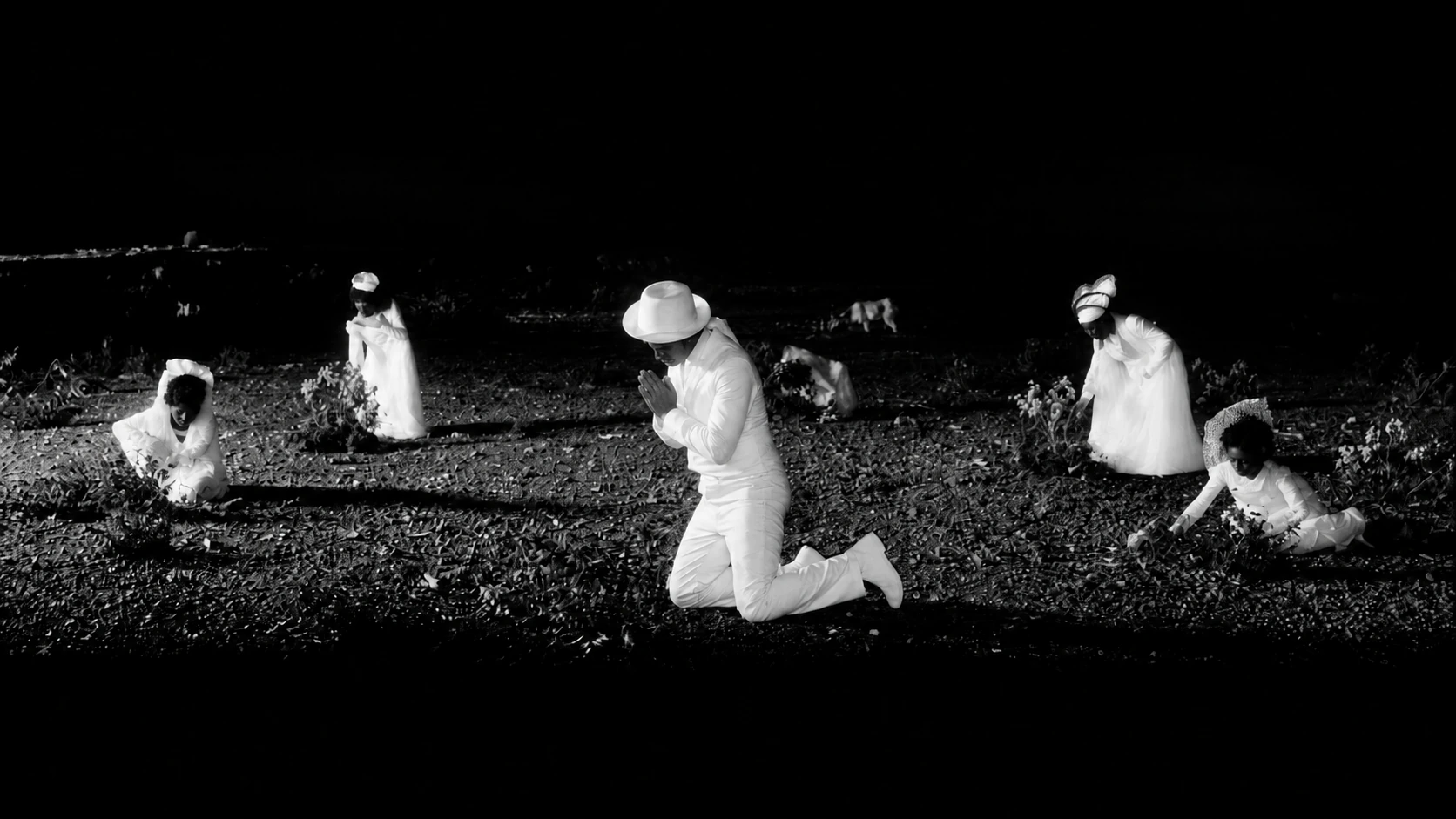 Small white figures are scattered across grass in the darkness.