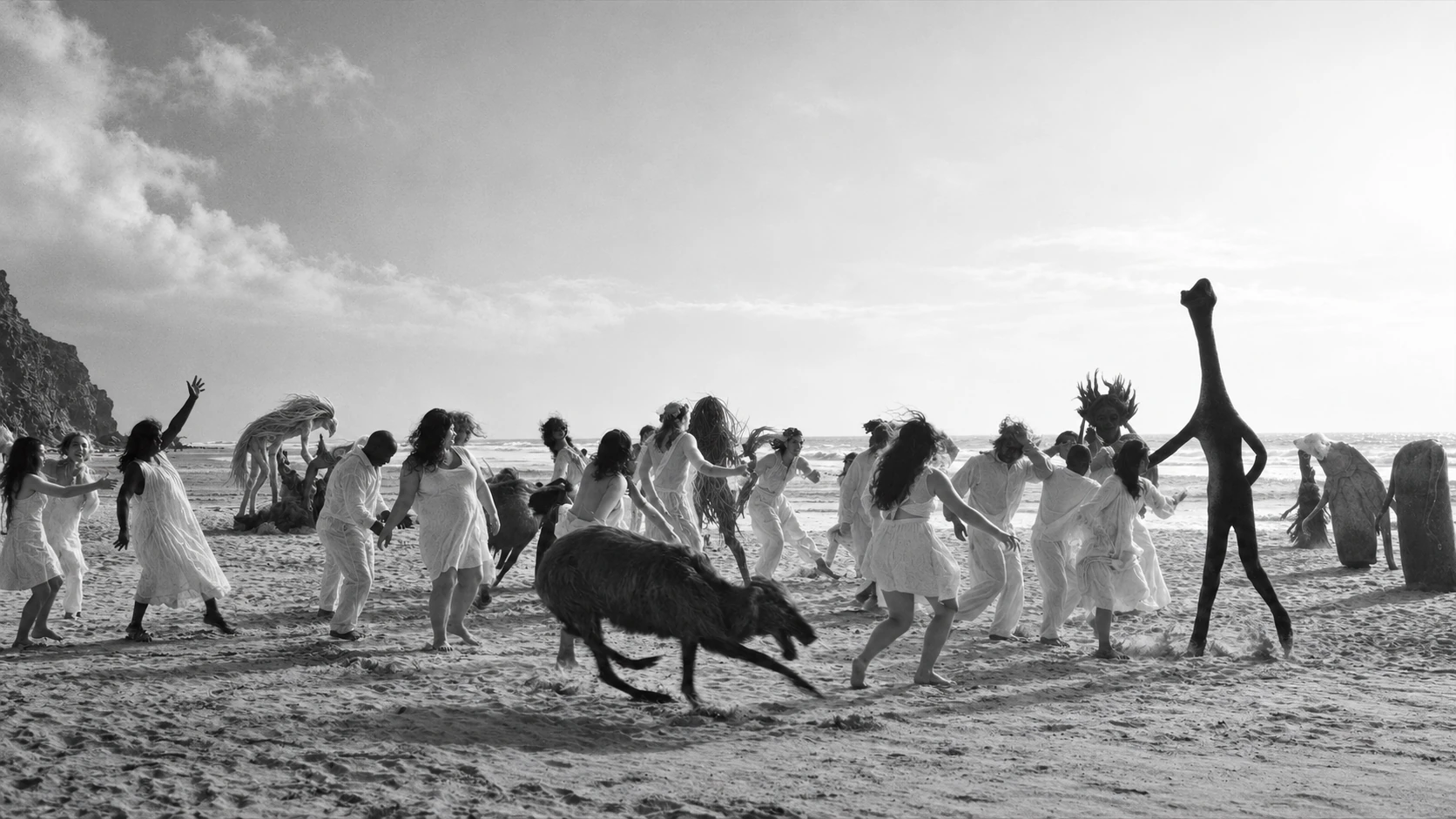 A procession of strange figures and creatures crosses an open landscape.